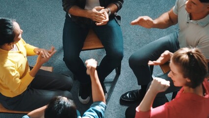 Top down aerial view of diverse business people hold wrist while sitting circle together. Faithful prayers holding wrist or hand of each other. Represented teamwork, unity, togetherness. Symposium.