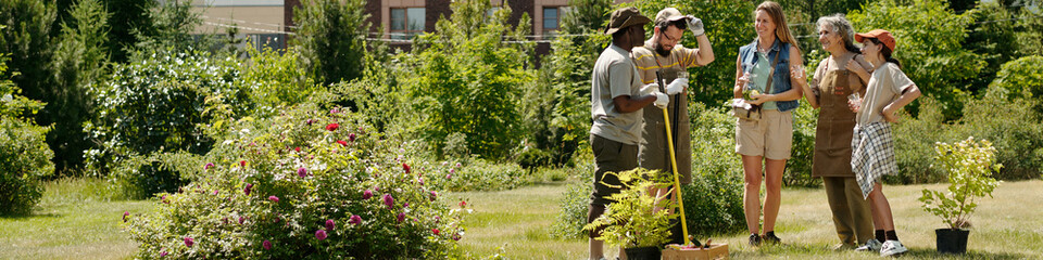 Group of multiethnic young adults and middle aged women standing outdoors discussing gardening...