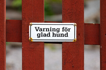 Warning Sign for Friendly Dog on Wooden Fence