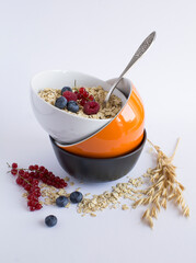 Bowl of oat flake and berries on a white background. Close-up. Location vertical.