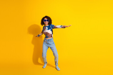 Charming young woman enjoying carefree moments dressed stylishly against a vibrant yellow...
