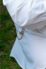 A person dressed elegantly in a white dress is sitting comfortably on a chair placed on the grass...