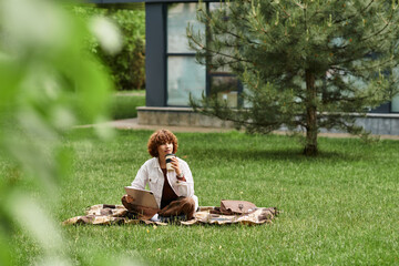 Freelancer enjoys productive summer morning in green park with laptop and coffee