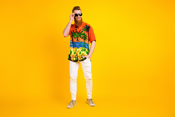 Fototapeta premium Stylish young man in vibrant tropical shirt on yellow background showing casual style and summer travel vibes