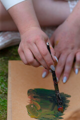 A person is skillfully applying paint with a brush on a blank piece of paper, creating a beautiful...