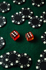 Red dice displaying numbers sit between various black casino chips on a green felt surface. The arrangement suggests a lively game night filled with excitement and opportunity for players