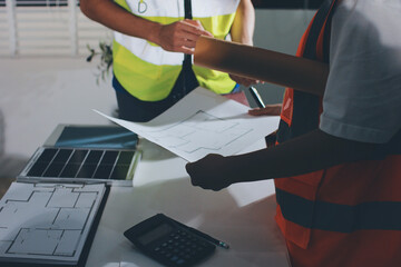 Closeup of team of industrial engineers meeting analyze machinery blueprints consult project on...