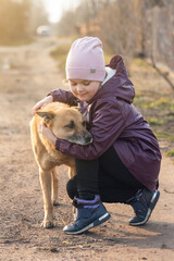 Adorable little girl hugging a large brown yard dog on a village street