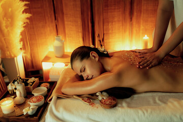 Woman customer having exfoliation treatment in luxury spa salon with warmth candle light ambient....