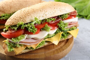 Tasty baguette sandwiches with ham, cheese and vegetables on grey table, closeup