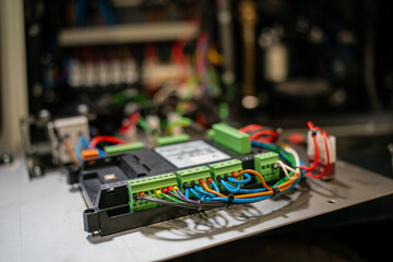 Industrial control circuit board with multicolored wiring and connectors mounted on metal plate,...
