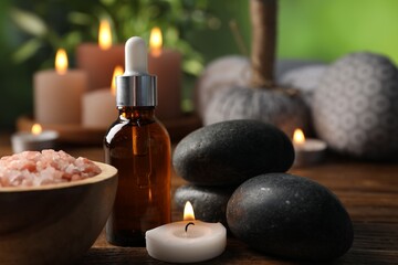 Spa composition with cosmetic products, stones and burning candle on wooden table against blurred...