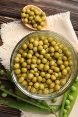 Pickled peas in jar and pods on wooden table, flat lay