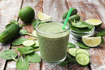 Tasty spinach smoothie and ingredients on wooden table, closeup