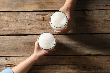 Friends with glasses of beer at wooden table, top view