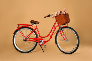 Bicycle with basket of beautiful flowers on pale orange background