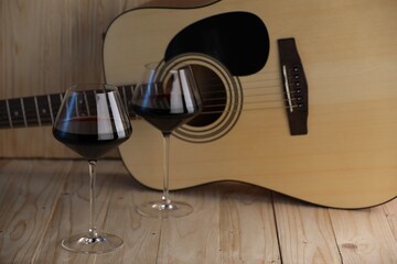 Acoustic guitar and glasses of red wine on wooden table. Space for text