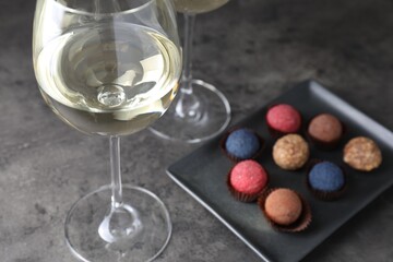 Tasty wine in glasses and truffle bonbons on grey table, closeup