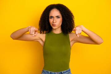 Young casual woman with curly hair on a vibrant yellow background poses with expressive hand...