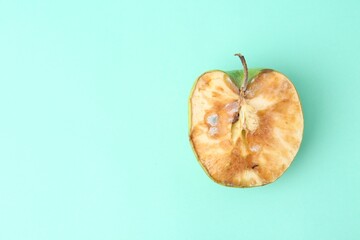 Half of spoiled apple on turquoise background, top view. Space for text