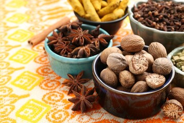 Different aromatic spices on orange tablecloth, closeup