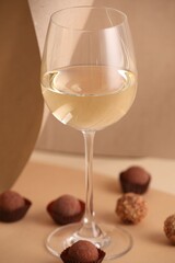 Delicious truffle bonbons and wine on beige background