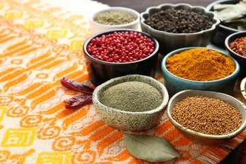 Different aromatic spices on orange tablecloth, closeup. Space for text