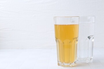 Glasses with clean and dirty water on white tiled table, closeup. Space for text