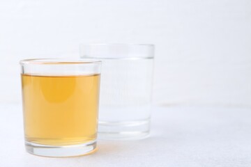 Glasses with clean and dirty water on light table, closeup. Space for text