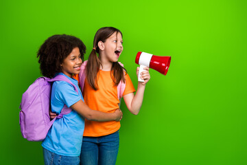 Two joyful girls with backpacks and a megaphone enjoying a lighthearted moment against a vibrant...