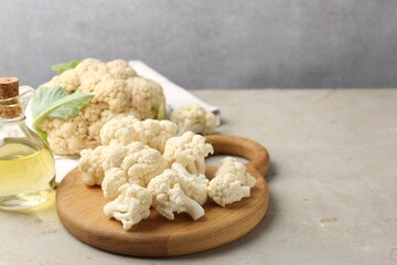 Fresh raw cauliflower florets and oil on light grey table, closeup. Space for text