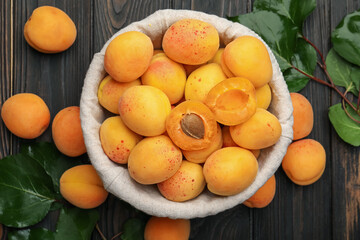 Fresh apricots and green leaves on wooden table, flat lay