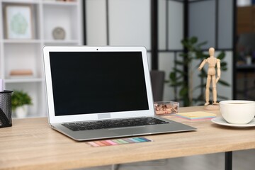 Modern laptop, coffee and stationery on wooden desk in office. Comfortable workplace