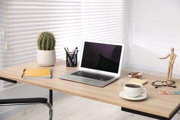 Modern laptop, coffee and stationery on wooden desk in office. Comfortable workplace