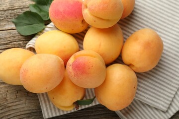 Fresh apricots and green leaves on wooden table, flat lay