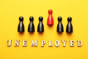 Word Unemployed and human figures on yellow background, flat lay