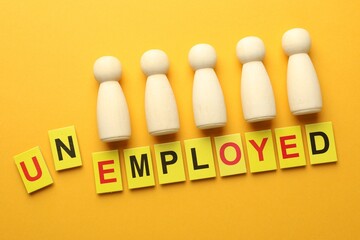 Word Unemployed and human figures on yellow background, flat lay