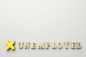 Word Unemployed and cross on light background, flat lay. Space for text