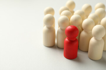 Unemployment. One red figure among wooden on light background, closeup. Space for text