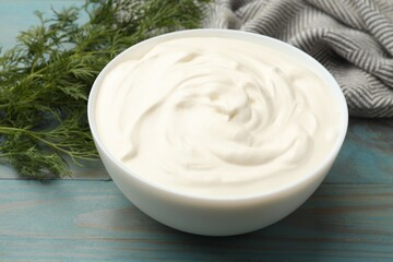 Tasty sour cream with dill on blue wooden table, closeup