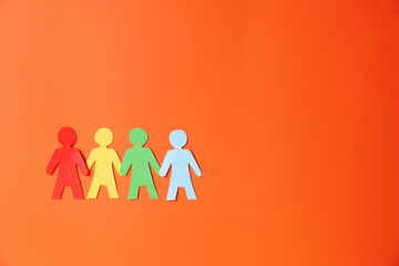 Paper figures of people holding hands on orange background, top view. Space for text