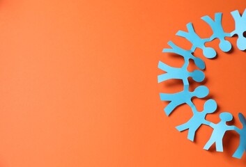 Paper figures of people holding hands on orange background, top view. Space for text