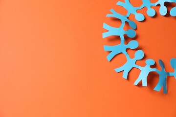 Paper figures of people holding hands on orange background, top view. Space for text