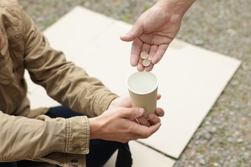 Man giving money to homeless person outdoors, closeup