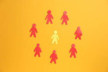 Many human paper figures on orange background, flat lay