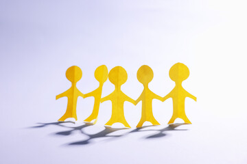 Paper figures of people holding hands on white background
