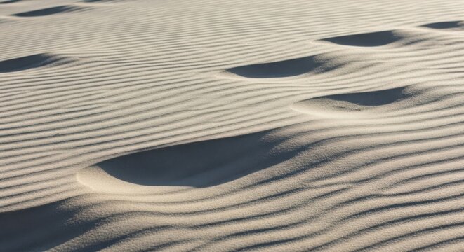 Intricate patterns of sand ripples on a desert dune, illuminated by warm, soft sunlight creating a serene texture