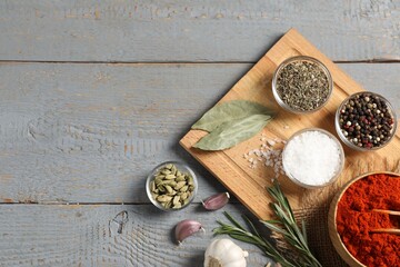 Different aromatic spices on grey wooden table, flat lay. Space for text
