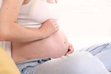Beautiful pregnant woman on bed at home, closeup. Space for text