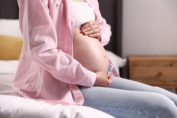 Beautiful pregnant woman on bed at home, closeup